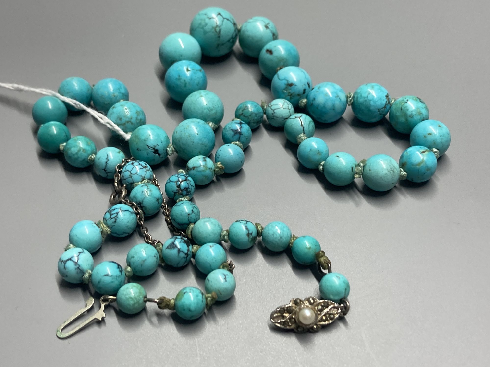 A continental graduated turquoise bead necklace, with marcasite and cultured pearl set white metal clasp, 57cm, gross 73 grams.